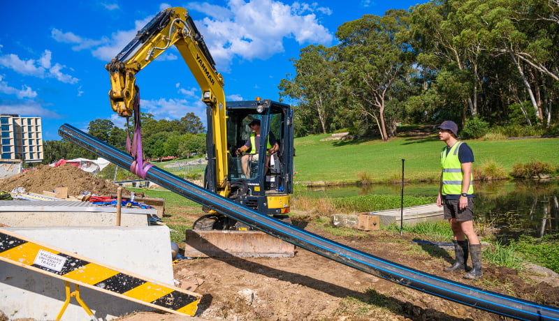 Man using excavator to lift the pipe